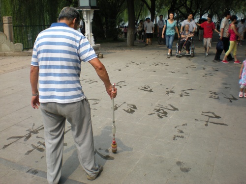 Un home practicando la so caligrafía a la entrada del parque Beihai (北海公園) en Beixín